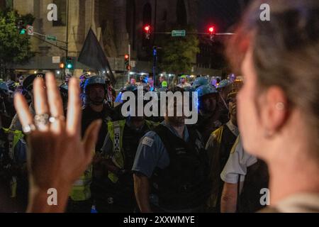 Chicago, États-Unis. 22 août 2024. Une activiste pro-palestinienne lève les mains en faisant face à une file d’officiers de police de Chicago occupant le bord d’Union Park après avoir défilé près du United Center, où se tient la Convention nationale démocrate, à Chicago, il le jeudi 22 août 2024. Des milliers de manifestants sont venus dans la ville pour protester contre le DNC et appeler à un cessez-le-feu à la guerre à Gaza. Crédit : Sipa USA/Alamy Live News Banque D'Images
