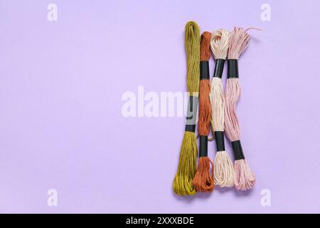 Différents fils mouline colorés sur fond lilas Banque D'Images