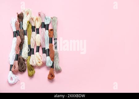 Différents fils mouline colorés sur fond rose Banque D'Images
