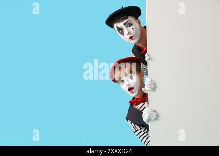 Couple de pantomimistes avec affiche blanche sur fond bleu Banque D'Images