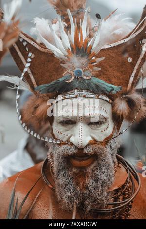Un homme de la province de Hela, Papouasie-Nouvelle-Guinée, avec une peinture pour le visage vibrante et une coiffe frappante ornée de plumes, symbolisant la fierté tribale. Banque D'Images
