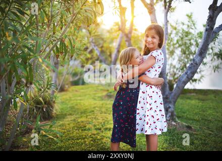 Happy funny soeurs embrasser ensemble dans l'heure du coucher du soleil Banque D'Images