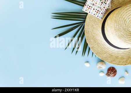 Voyage, concept de vacances. Chapeau avec coquillages, feuille de palmier, passeport sur fond bleu. Banque D'Images