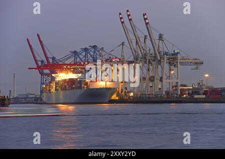 Grand porte-conteneurs au port de hambourg au coucher du soleil Banque D'Images