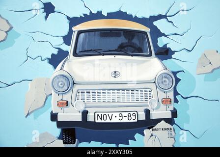 Voiture trabant est-allemande traversant le mur de berlin. graffiti sur la galerie côté est berlin Banque D'Images