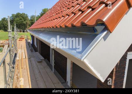 Le zinc gouttière avec des tuiles du toit et les échafaudages à new house Banque D'Images