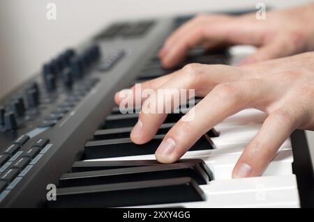 Gros plan de mains masculines jouant du piano dans le studio Banque D'Images