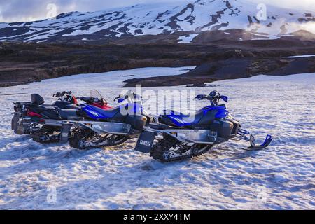 ISLANDE, 04 JUILLET : quatre motoneiges stationnées dans une rangée dans une épaisse neige hivernale en Islande dans un paysage hivernal froid désolant le 04 juillet 2013 à I. Banque D'Images