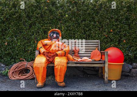 DJUPIVOGUR, ISLANDE, 21 JUIN : mannequin d'une sorcière au visage laid et effrayant dans une combinaison orange est assis sur un banc en bois le 21 juin 2013 à Djupivogur, Banque D'Images