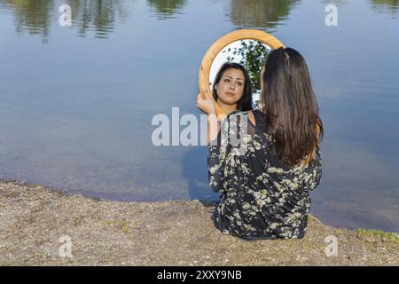 Jeune femme à la recherche à l'image miroir près de l'eau Banque D'Images