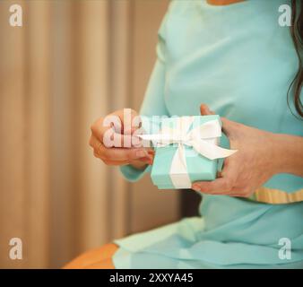 Femme tenant une petite boîte bleue avec un ruban blanc dans ses mains Banque D'Images