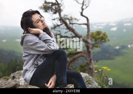 Fille de rêve se trouve sur le bord de la falaise et à la recherche à la vallée de soleil et montagnes Banque D'Images