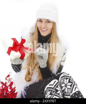 Young smiling woman holding gift décoré de ruban rouge à l'extérieur. L'heure d'hiver Banque D'Images