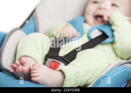 Little smiling baby enfant attaché avec la ceinture de sécurité en voiture de sécurité conducteur Banque D'Images