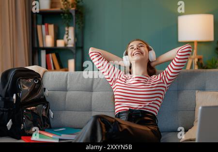 Enfant heureux est assis sur le canapé. L'adolescente se détache après l'école. Banque D'Images