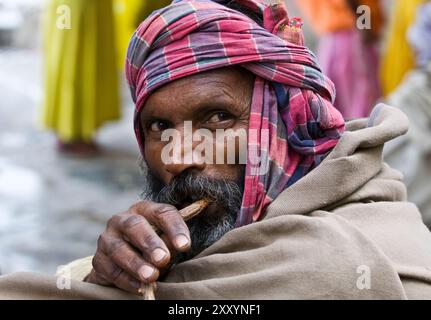 Un homme bengali se nettoyant les dents avec une brosse à dents traditionnelle à Kolkata, en Inde. Banque D'Images