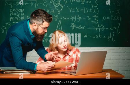 L'enseignant collabore avec ses collègues. Retour à l'école et concept d'éducation. Jeune enseignant près du tableau noir dans la salle de classe de l'école. Tableau noir pour copie Banque D'Images