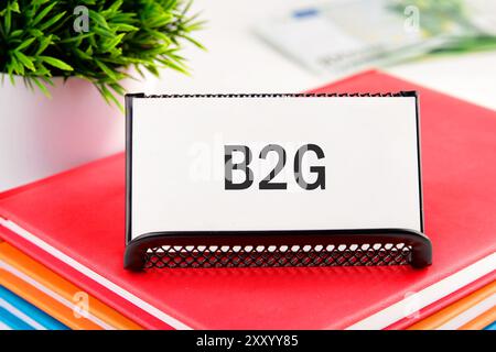 B2G - abréviation de Business to Government. B2G écrit sur une carte de visite debout dans un stand sur des ordinateurs portables Banque D'Images
