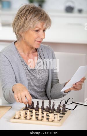 femme âgée jouant aux échecs à la maison Banque D'Images