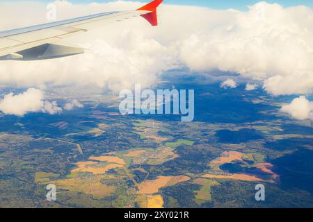 Vue depuis une fenêtre d'avion des champs et des forêts de la Russie centrale près de Moscou. Beaux nuages blancs moelleux. Banque D'Images