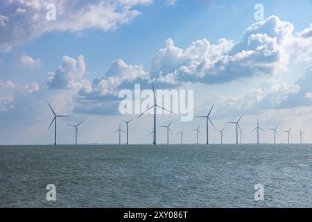 WindEnergie auf See - Windpark FryslÃn Friesland Niederlande, Breezanddijk im août 2024 : Ein Offshore Windpark mit blauen leicht bewölktem Himmel. Die Anlage ist vor dem Deich auf der A7 Autobahn zwischen dem IJsselmeer und dem Wattenmeer. *** Énergie éolienne en mer Parc éolien Fryslân Friesland pays-Bas, Breezanddijk en août 2024 un parc éolien offshore avec un ciel bleu légèrement nuageux L'éolienne est en face de la digue sur l'autoroute A7 entre l'IJsselmeer et la mer des Wadden Banque D'Images