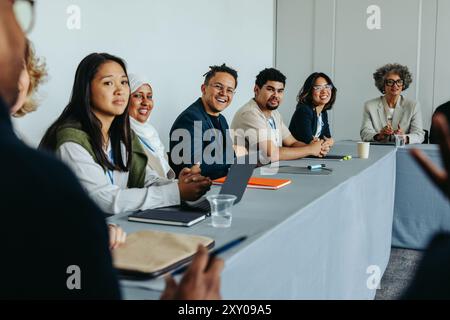 Groupe diversifié d'employés engagés dans une discussion d'affaires lors d'une réunion de stratégie. Travail d'équipe professionnel et collaboration dans un bureau moderne envi Banque D'Images