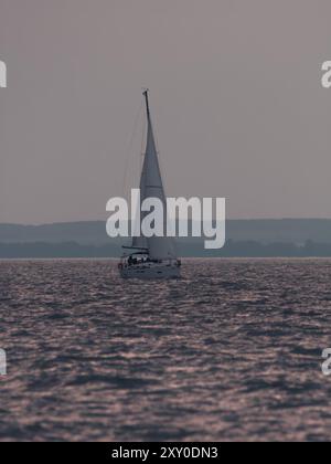 Voilier sur le lac Balaton dans la brume grise après le coucher du soleil Banque D'Images