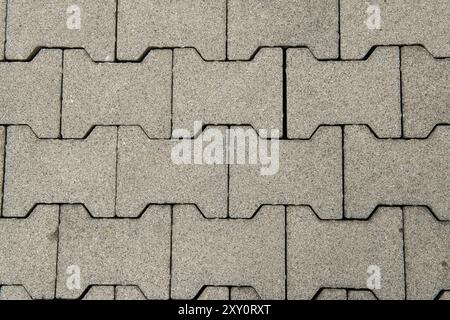 les briques entrelacées texturées pour revêtements de sol, en béton interconnecté, offrent un design fonctionnel et résistant aux intempéries. L'installation sans mortier. Banque D'Images