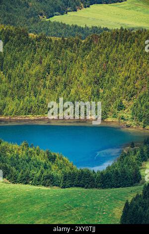 Un paysage à couper le souffle mettant en valeur un lac bleu profond niché parmi les forêts denses et verdoyantes et les prairies luxuriantes des Açores, capturant la sérénité et la nature intacte Banque D'Images