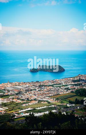 Cette superbe photographie capture une vue aérienne panoramique d'une ville animée des Açores, mettant en valeur la végétation luxuriante, la disposition structurée de la ville, et Banque D'Images