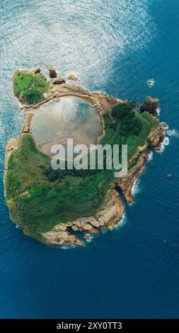 Vue aérienne d'une île luxuriante et verdoyante des Açores, avec un littoral spectaculaire, des falaises escarpées et un lac de cratère volcanique serein, entouré Banque D'Images