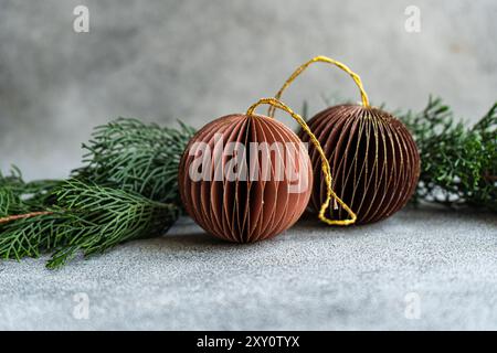 Gros plan d'ornements de Noël sophistiqués en papier brun et de branches de pin sur une surface de béton rugueuse. Banque D'Images