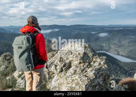 Un randonneur profite de la vue panoramique sur les vallées verdoyantes et les montagnes de Vilvestre, Salamanque bien équipée avec un sac à dos et équipement de plein air, t Banque D'Images