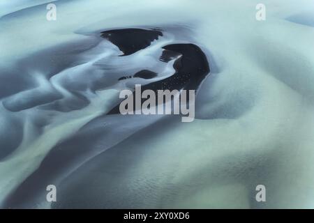 Superbe photo aérienne capturant les motifs complexes et les textures d'un glacier sur la côte sud de l'Islande, mettant en valeur la beauté naturelle et Banque D'Images