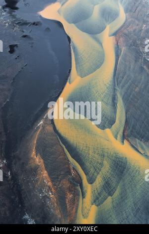 Vue de dessus de la rivière Holtsos en Islande serpente, coupant à travers des paysages luxuriants, ses eaux un choc vibrant de tons sombres et clairs, capturé Banque D'Images