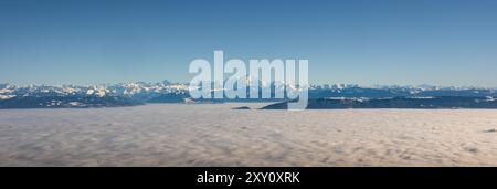 Un panorama à couper le souffle montrant une vaste mer de nuages sous un ciel bleu clair, avec les sommets majestueux des Alpes françaises et suisses, dont le Mont Bl Banque D'Images