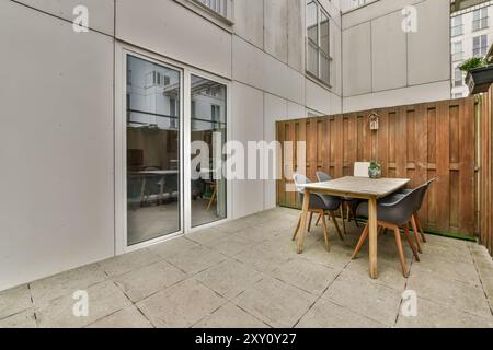 Un patio contemporain doté d'une table à manger en bois, de chaises et d'une clôture d'intimité dans un cadre urbain. Banque D'Images