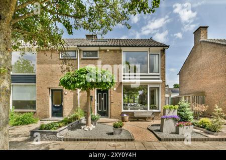 Une maison jumelée moderne avec un jardin magnifiquement paysagé, de grandes fenêtres et un ciel dégagé au-dessus de la tête. Banque D'Images