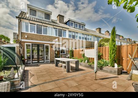 Une cour arrière spacieuse de banlieue avec une terrasse pavée, un espace de jardinage et un cadre extérieur familial. Banque D'Images