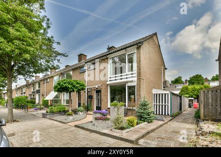 Une maison de briques de banlieue chaleureuse avec un jardin bien entretenu et une allée privée sous un ciel bleu. Banque D'Images