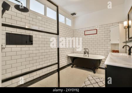 Cette luxueuse salle de bains dispose d''une baignoire vintage sur pieds, d''une douche spacieuse à l''italienne, de carrelages de métro et d''équipements modernes alliant classique et mépris Banque D'Images