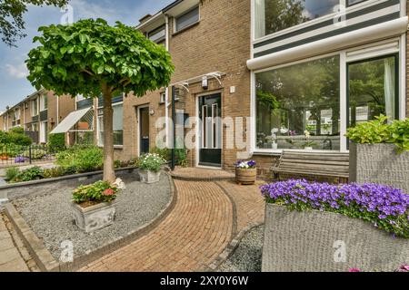 Une charmante maison de banlieue avec un beau jardin avec une variété de plantes et un chemin de briques courbé menant à la porte d'entrée. Banque D'Images