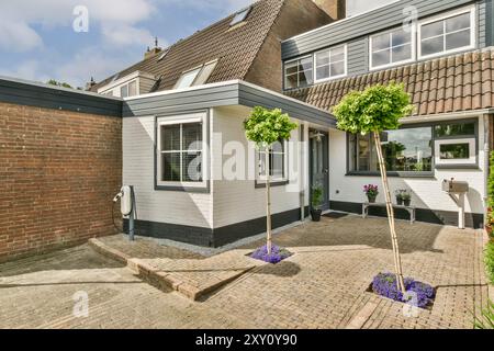 Charmante maison de banlieue avec revêtement blanc et bel aménagement paysager, y compris les arbres topiaires. Banque D'Images