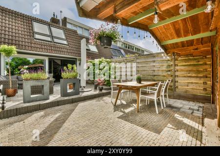 Cette image capture une configuration de patio confortable dans un cadre de banlieue avec des meubles bien aménagés et des plantes décoratives améliorant l'atmosphère chaleureuse. Banque D'Images