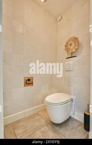 Une salle de bains contemporaine avec des toilettes blanches sur fond de carreaux blancs propres avec une pièce décorative en bois. Banque D'Images