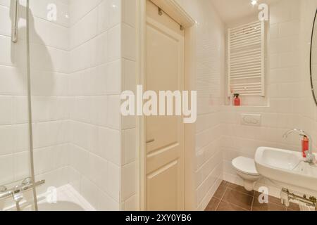 Cette image met en valeur un design de salle de bains propre et contemporain, avec des carreaux de métro blancs, une douche en verre et des luminaires modernes. Banque D'Images