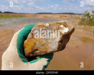 Grand fragment de calcédoine humide à la main, rockhounding, photo de terrain Banque D'Images