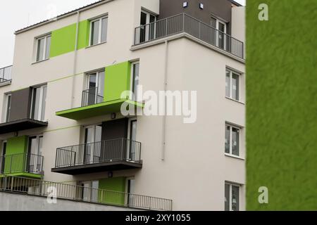 Immeuble d'appartements moderne avec des accents verts vibrants, plusieurs balcons et de grandes fenêtres, mettant en valeur l'architecture résidentielle urbaine contemporaine. Banque D'Images