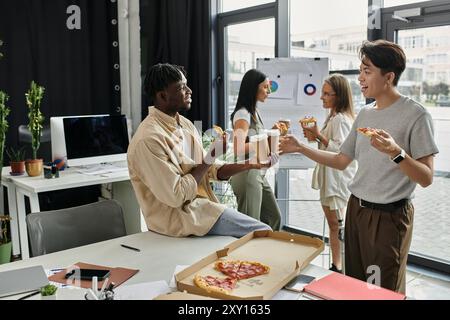 Quatre jeunes collègues font une pause au travail, dégustant pizza et café dans un bureau moderne. Banque D'Images