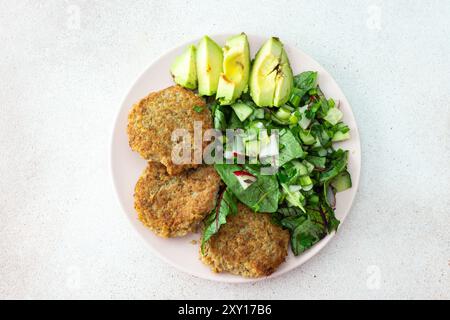 Côtelettes de quinoa et salade mixte avec avocat et radis, kiwi et eau au citron, délicieux petits déjeuners copieux, assiette végétalienne Banque D'Images